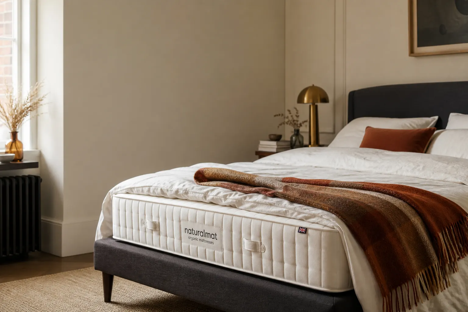 A neatly made double bed in a bright UK bedroom with white linen and a wool throw, no people in shot