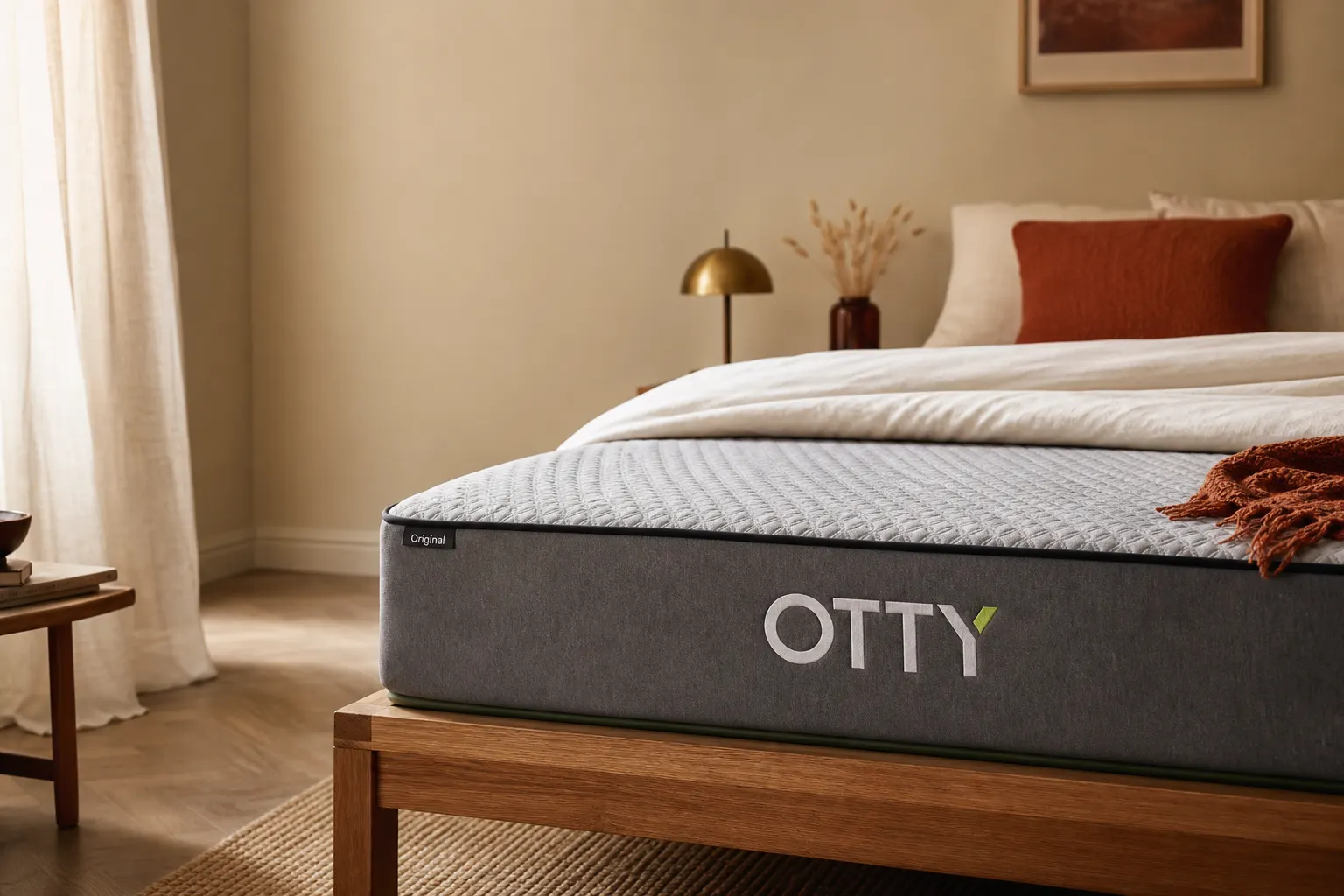 OTTY Original Hybrid mattress on a wooden bed frame in a softly lit bedroom, white duvet folded back to show the quilted cover
